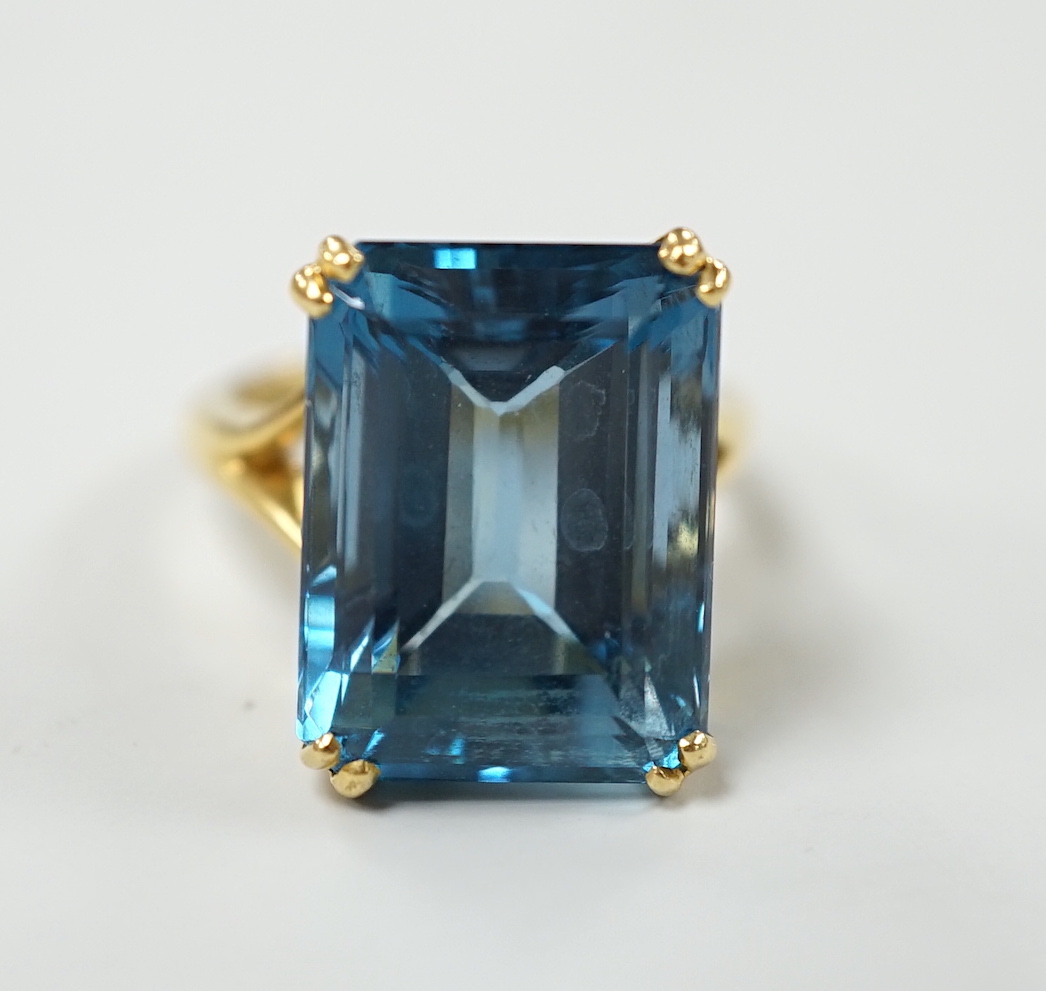 An 18ct and emerald cut blue topaz set dress ring, size K, gross weight 11 grams.